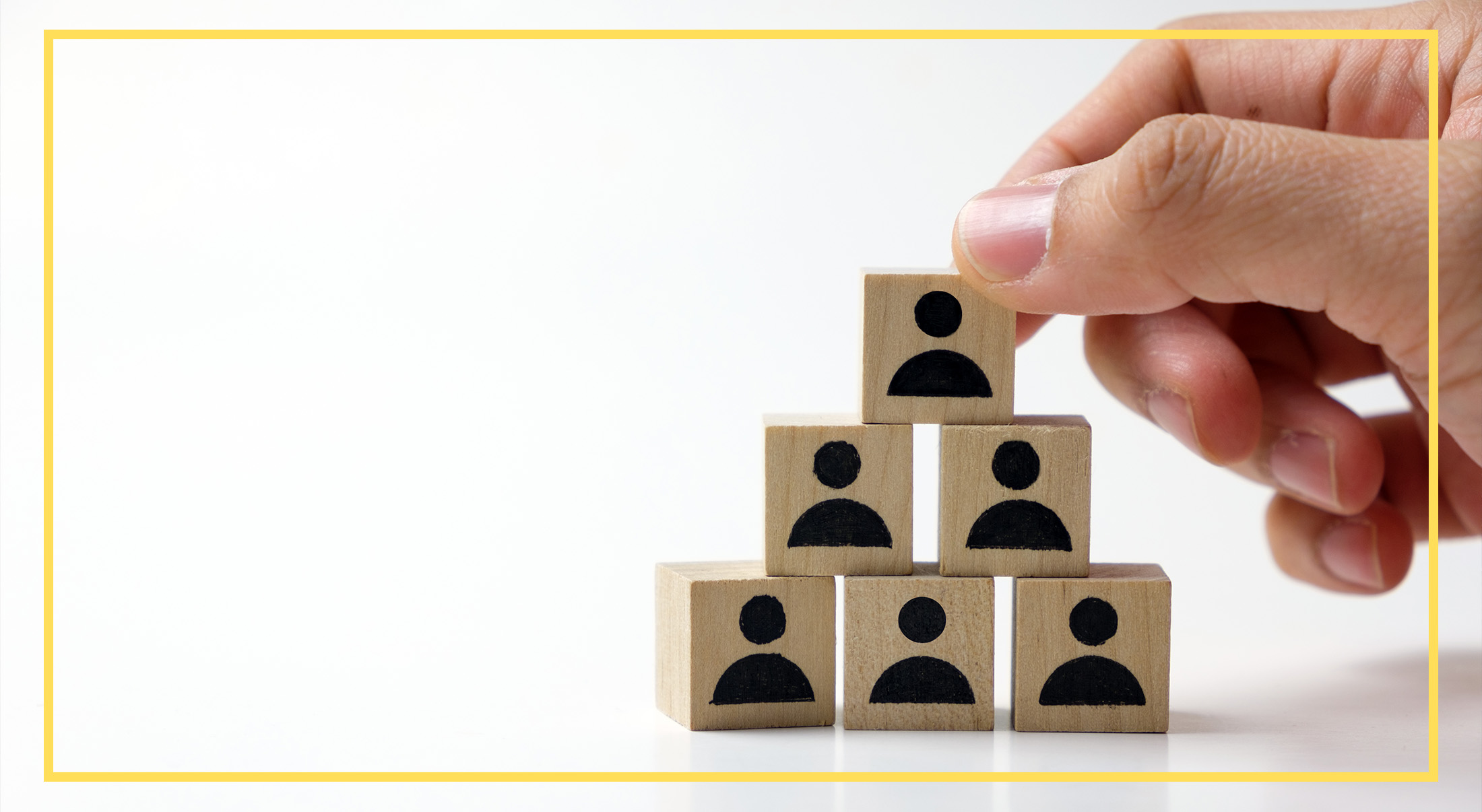 A hand stacks wooden blocks with person icons into a pyramid on a white background, symbolizing growth in energy sector employment.