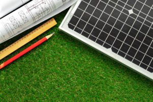 People using a solar savings calculator Blueprint roll and solar panel home project close up