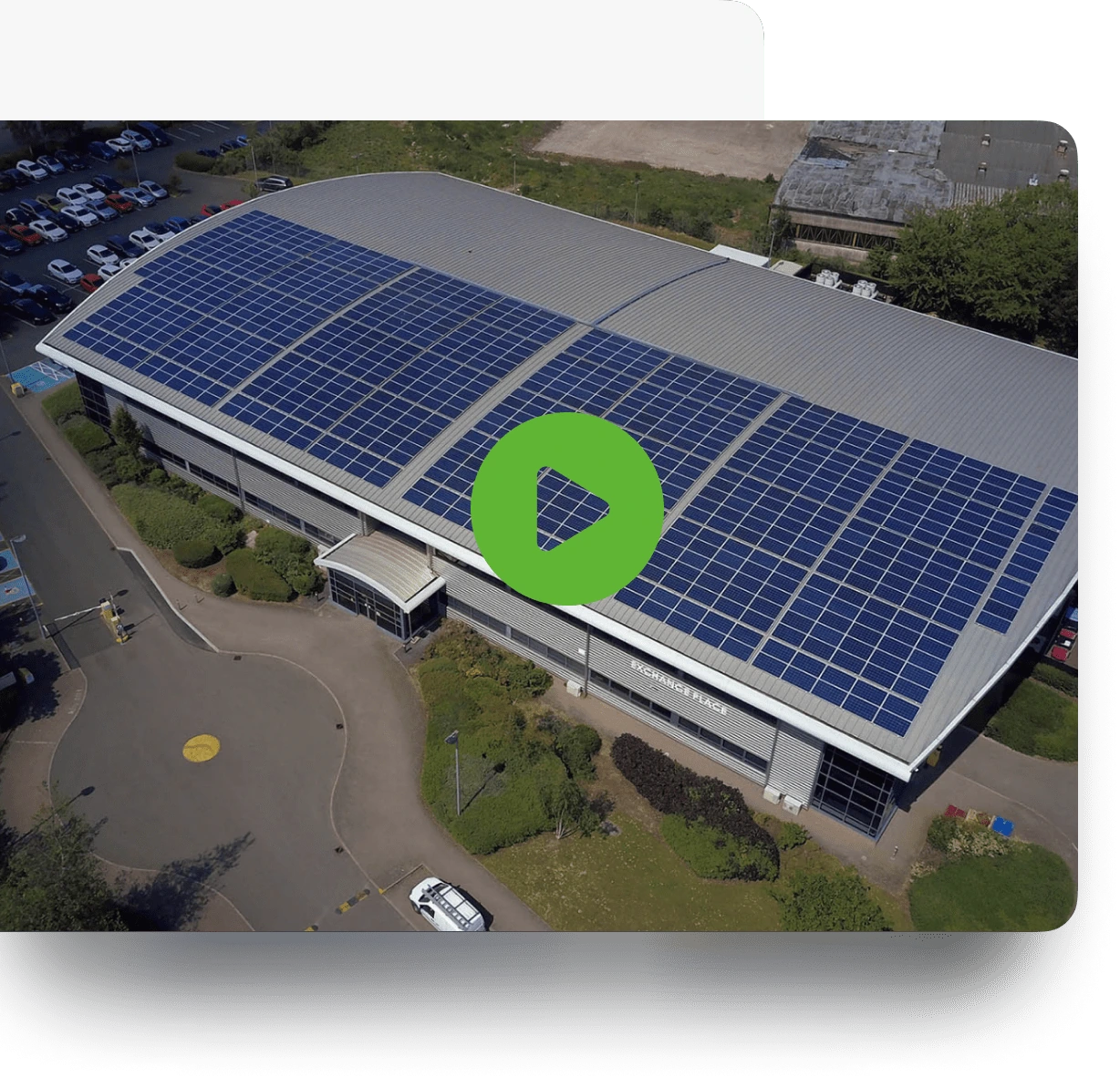 Aerial view of a large building with solar panels on its roof, labeled 'EXCHANGE PLACE,' surrounded by a parking lot.