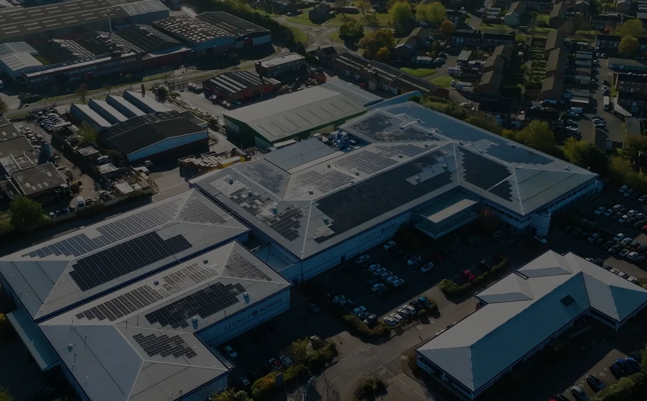 Industrial complex with solar-panel roofs, cars, and green surroundings.