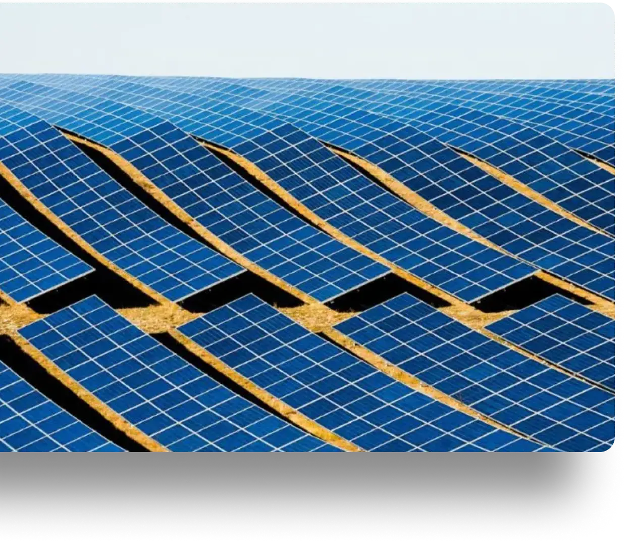 Wave-like array of blue solar panels on brown dry ground under a sunny sky.