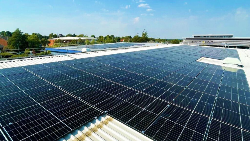 Aerial view of a building with 'LINNEY CREATE' signage and solar panels covering most of its rooftop."