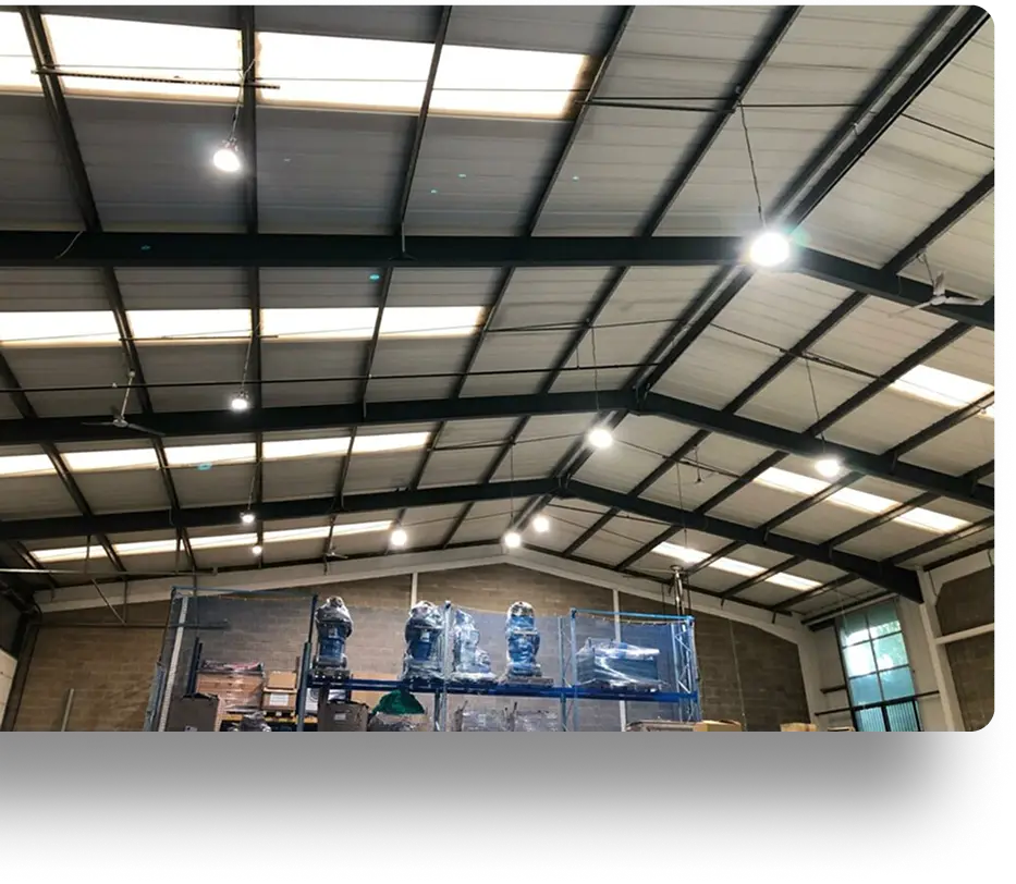 Scaffolding structure covered with plastic sheets inside an industrial warehouse with metal beam ceiling and lights.