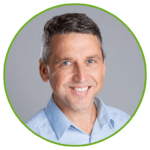 Person in light blue collared shirt, short dark hair, framed by green circle on plain gray background.