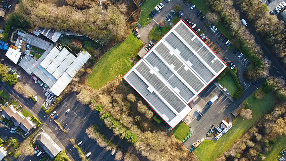 The image is an aerial view of a large building with a parking lot and surrounding areas.