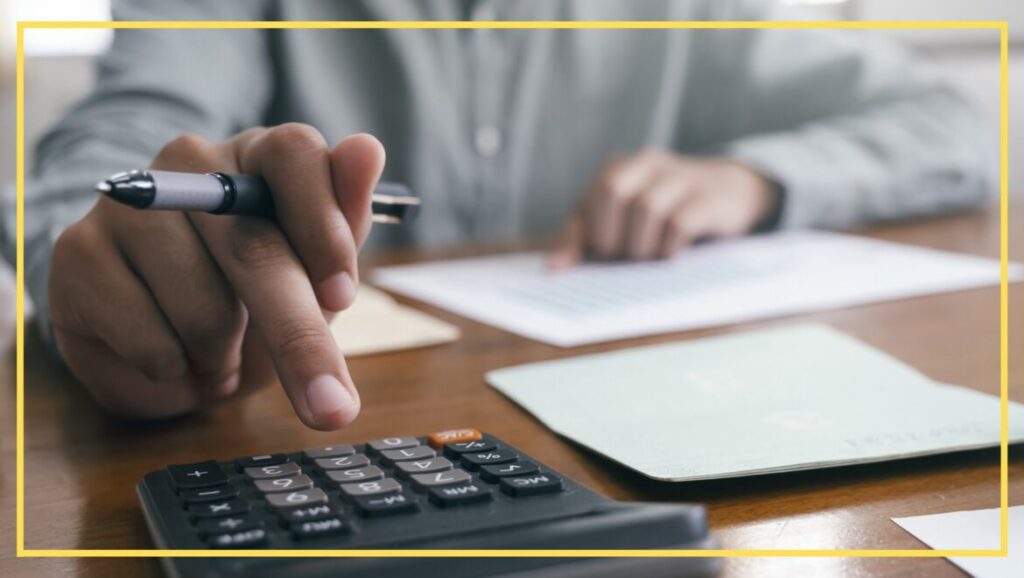 Someone using a calculator while holding a pen, seemingly engaged in financial tasks or paperwork.