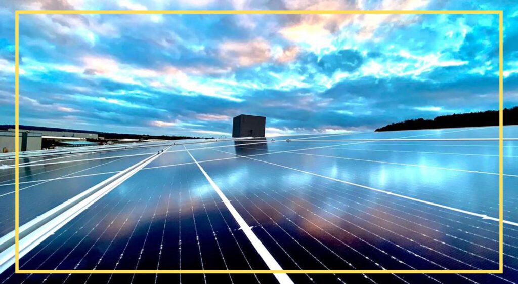 Rooftop solar panels reflecting sky hues, with a building in the backdrop.
