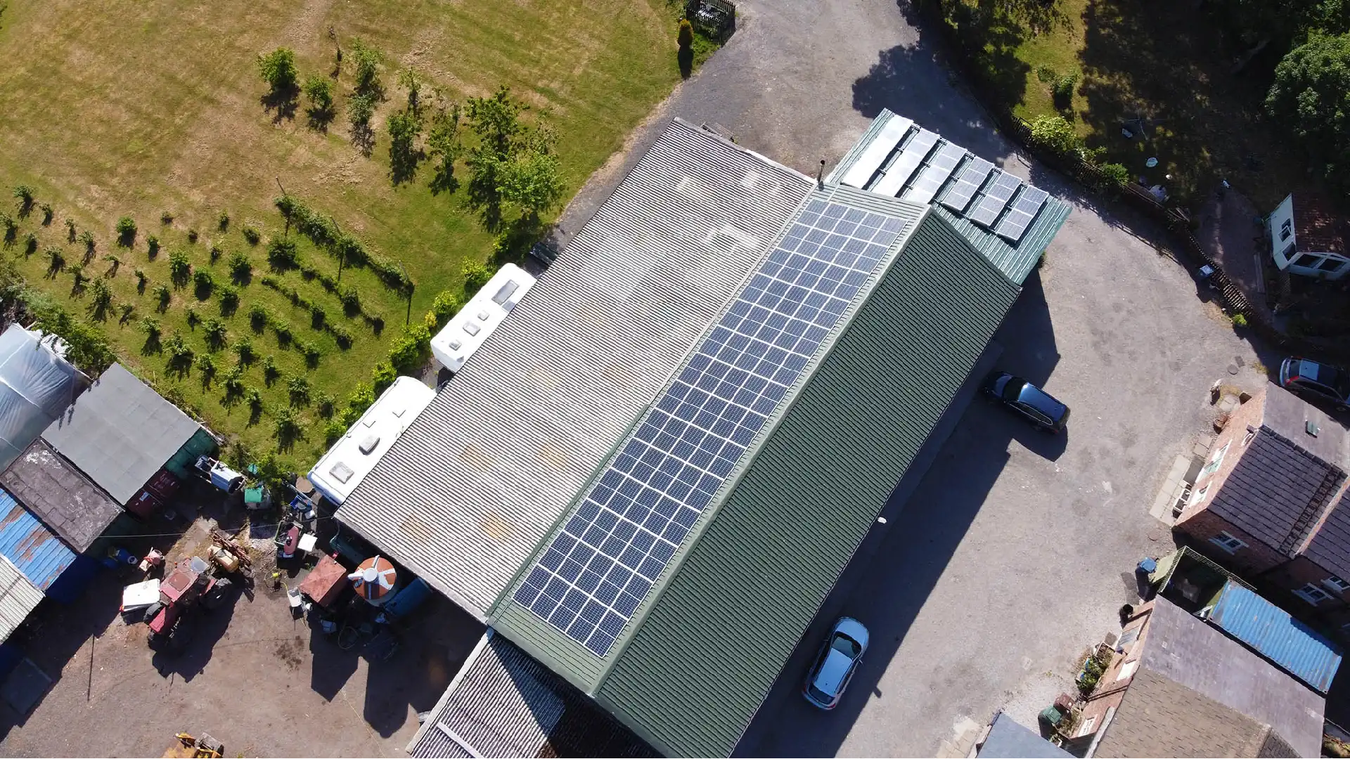 erial view of a building with solar panels on its roof and parked white vehicles.