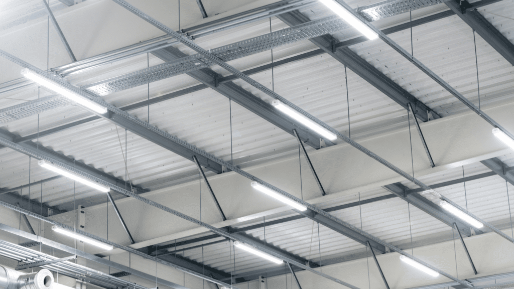 Industrial ceiling with metal beams, fluorescent lights, and ventilation ducts providing illumination and airflow." This keeps the description concise while staying within the 100-character limit. Let me know if you’d like any refinements!