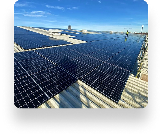 Rooftop with large solar panels by AK Sheet Metal Fabrications gleams under blue sky. A person in reflective gear observes the solar installation from a distance.