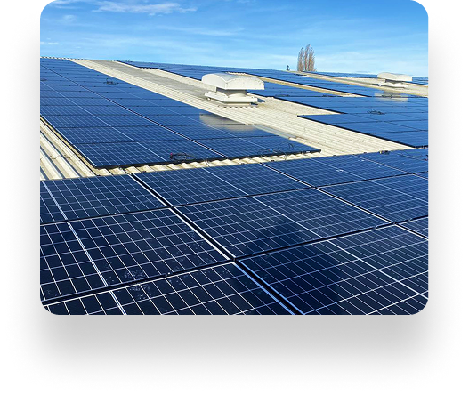 A rooftop lined with AK Sheet Metal Fabrications solar panels under a clear blue sky. Panels are neatly arranged, reflecting sunlight, with roof access structures visible.