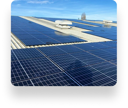 A rooftop lined with AK Sheet Metal Fabrications solar panels under a clear blue sky. Panels are neatly arranged, reflecting sunlight, with roof access structures visible.