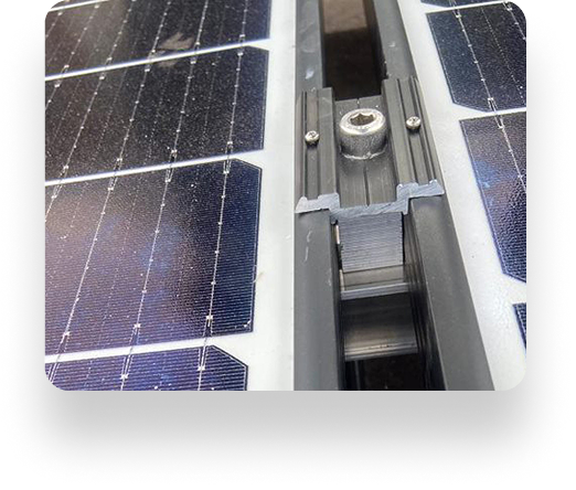 Close-up of two solar panels on a metal and plastic bracket system against Alt Valley backdrop, showing grid pattern, visible screws, and central track.