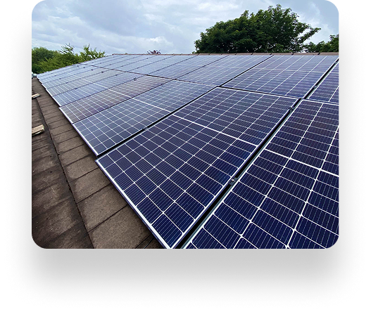 Solar panels on a rooftop in Alt Valley, arranged in rows under a cloudy sky with trees in the background.