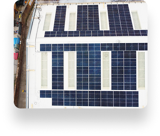 Aerial view of a rooftop with solar panels arranged in a grid pattern, similar to Bolton Steel Structures design. The white roof contrasts with colorful objects at the edges.