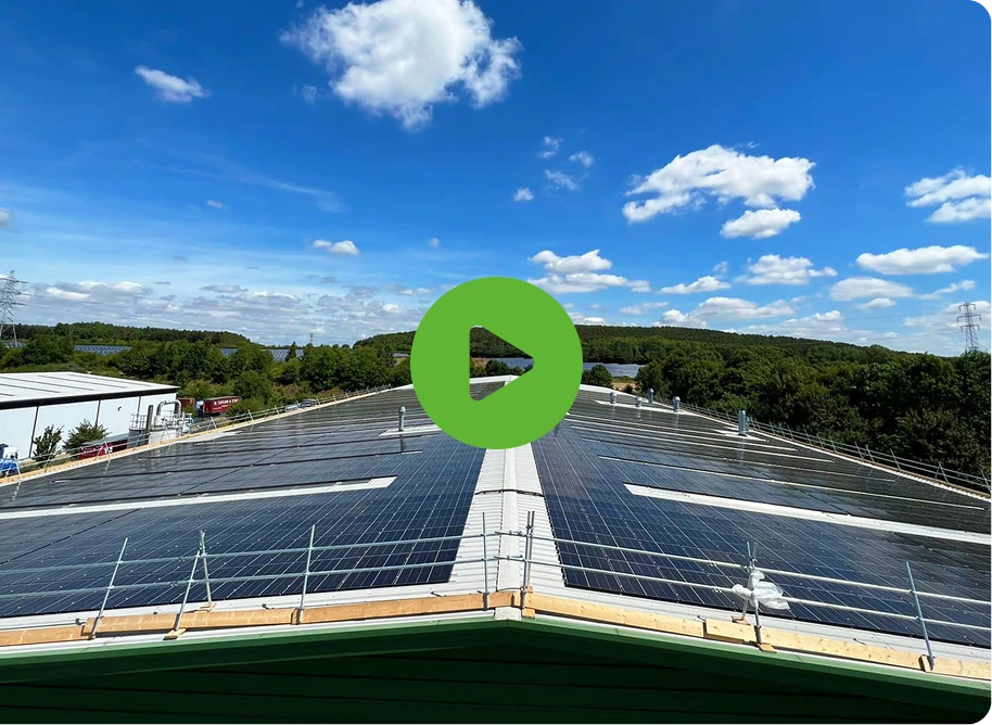 Rooftop with solar panels under a blue sky with clouds; Integrated Doorsets Solutions visible. Greenery surrounds the scene, and a green play button icon is in the center.