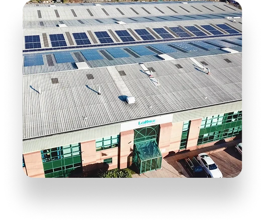 Aerial view of a large industrial building with solar panels on the roof, belonging to Laltex Group. The building has green windows and a glass-covered entrance.