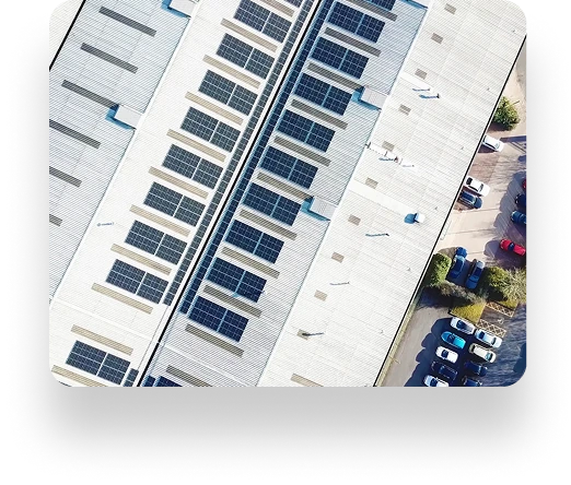 Aerial view of an industrial building with solar panel-covered roof, a full parking lot beneath, and lush greenery around, showcasing Laltex Groups eco-friendly initiatives.