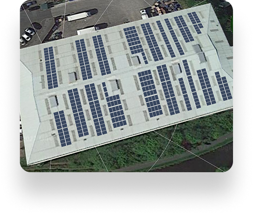 Aerial view of Lancs Farms large white-roofed building covered with solar panels, surrounded by greenery and parked vehicles.
