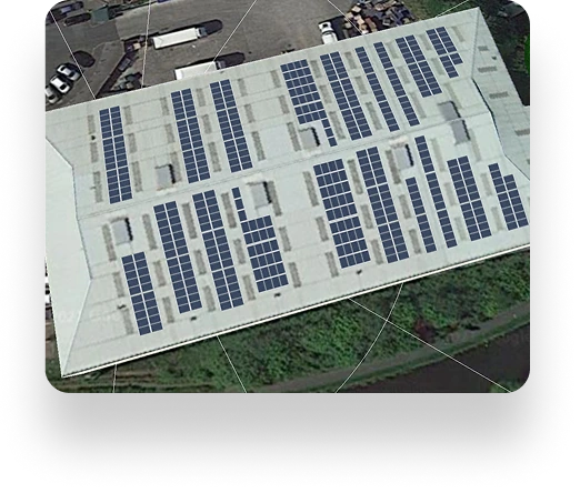Aerial view of Lancs Farms large white-roofed building covered with solar panels, surrounded by greenery and parked vehicles.