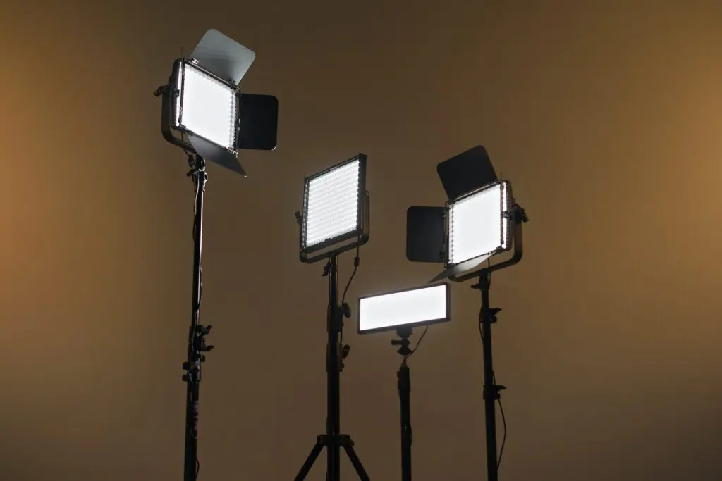 Four studio lights with barn doors, positioned on stands, emitting bright white light against a plain background.
