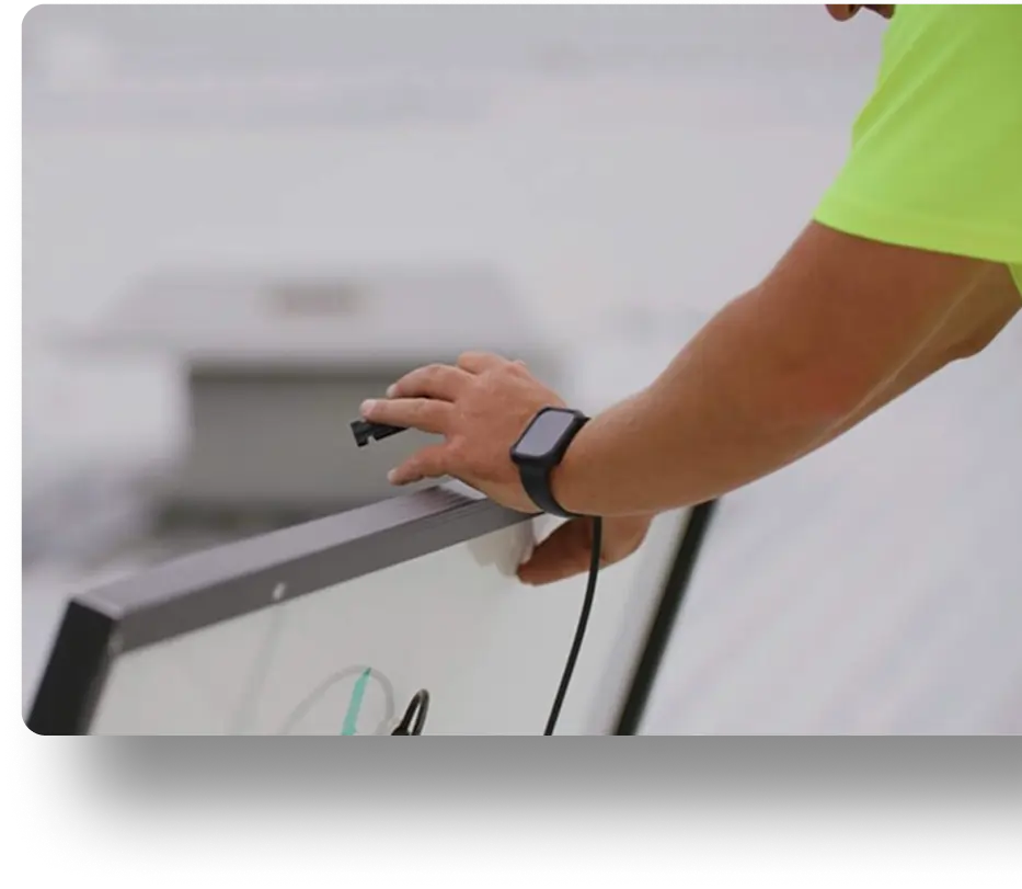 Person in a bright green shirt connects a cable to a solar panel on a rooftop.