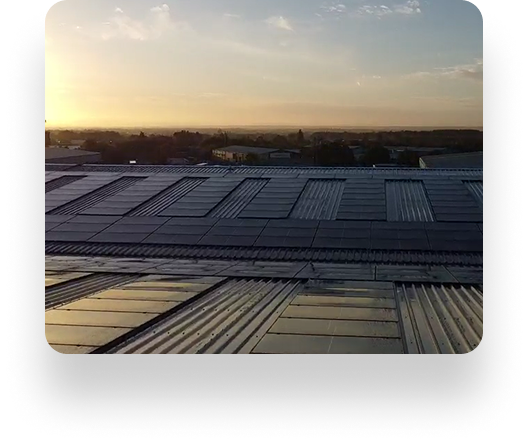 Solar panels on a rooftop with Pyroguard glass reflecting sunset light. A partly cloudy sky and distant buildings enhance the sustainable cityscapes serene ambiance.