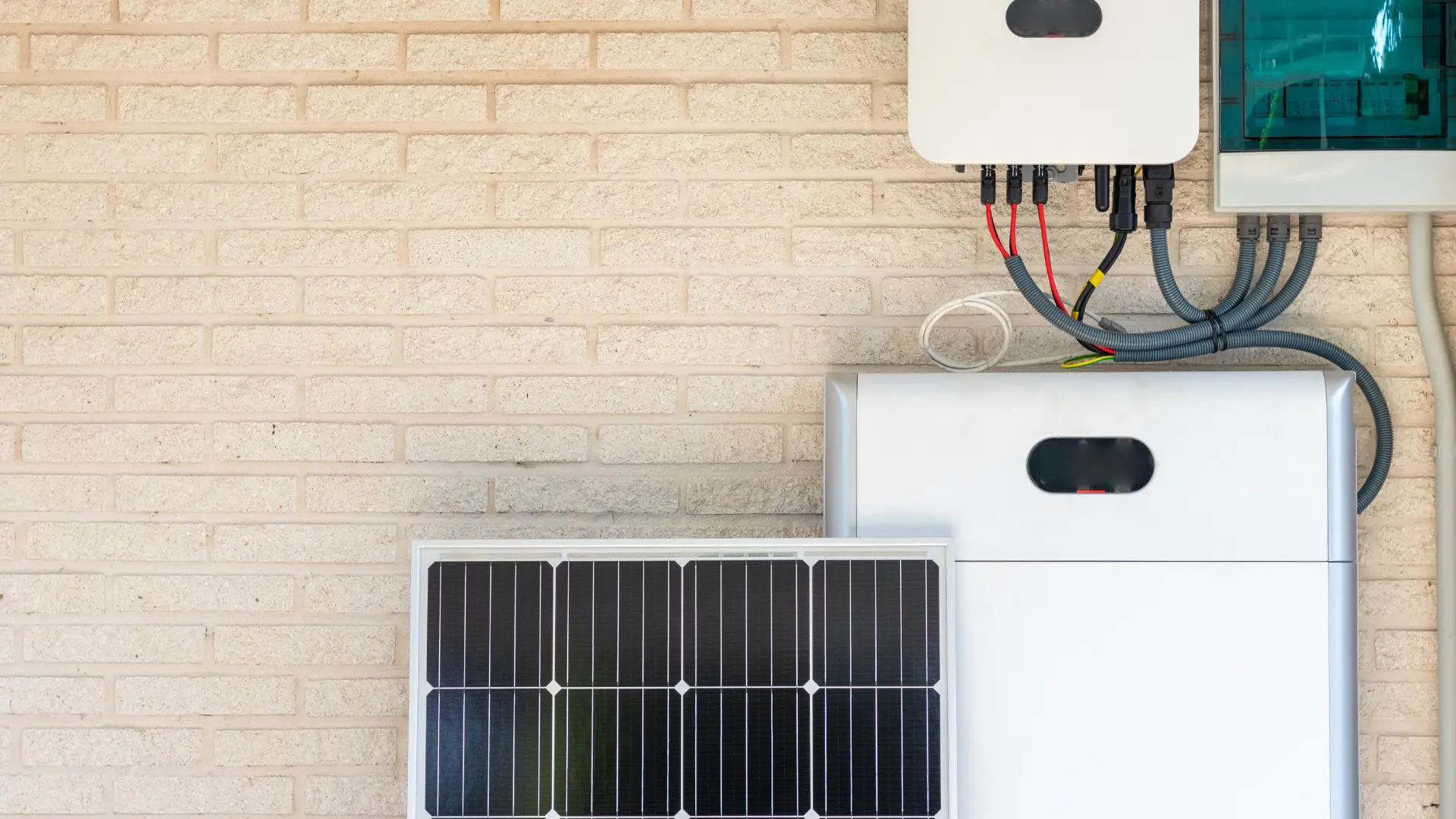 Solar panel, inverter, and wiring on a brick wall showcasing a typical residential setup.