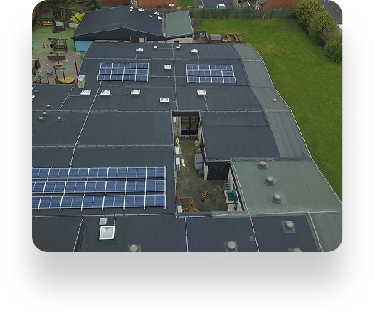 Aerial view of St Andrews Primary School, featuring solar panels on the roof. The building is surrounded by grass, with skylights and vents alongside the panels.