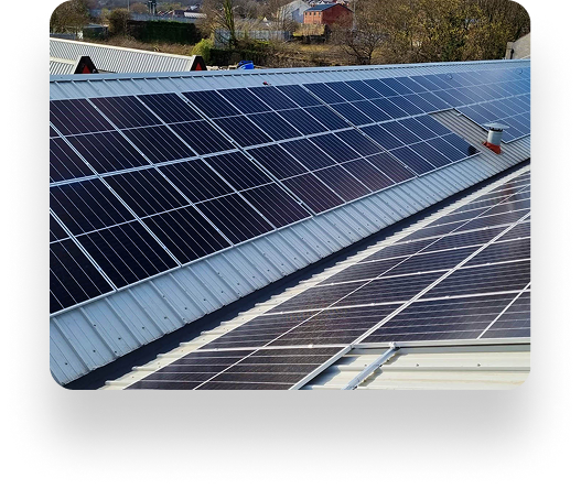 Rooftop solar panels on industrial buildings under a clear sky, optimized by TBE Precision, with trees and other structures in the background.