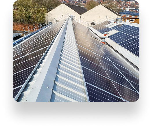 Rooftop solar panels from TBE Precision align perfectly under a clear sky on a metal roof, surrounded by trees and neighboring rooftops in the background.