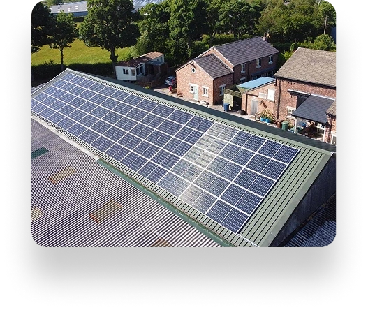 Rooftop solar panels at The Farm Burscough on a sloped roof, surrounded by trees and houses. Panels are arranged in rows to efficiently capture sunlight.