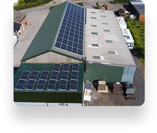 Aerial view of The Farm Burscough: Two industrial buildings with green roofs and solar panels. The left building has more panels. Vehicles and lush greenery surround.