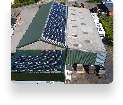Aerial view of The Farm Burscough: Two industrial buildings with green roofs and solar panels. The left building has more panels. Vehicles and lush greenery surround.
