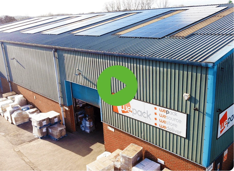An industrial warehouse with solar panels on the roof features WePacks logo and slogan: we pack, we source, we store, we deliver. Outside, pallets and boxes are stacked. A green play button is visible.