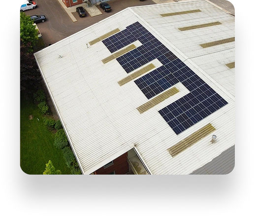 Aerial view of Westbrook Industrials large white building with solar panels on the roof, surrounded by green grass and a few parked cars.