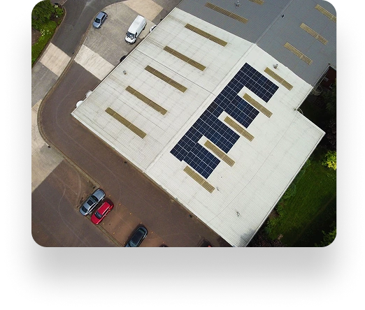 Aerial view of Westbrook Industrials solar-panel-covered roof, surrounded by parked cars and green landscape.