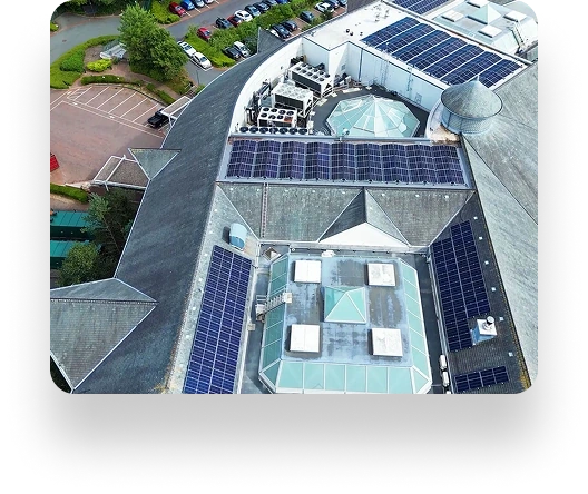Aerial view of a building roof with solar panels, skylights, and vents. Zen Internet boosts connectivity. Surrounding parked cars and trees add to the harmony.
