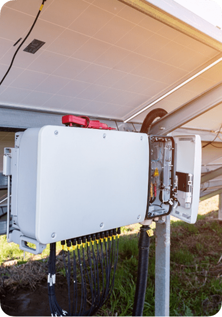 Open electrical box on a pole with solar panels in the background.