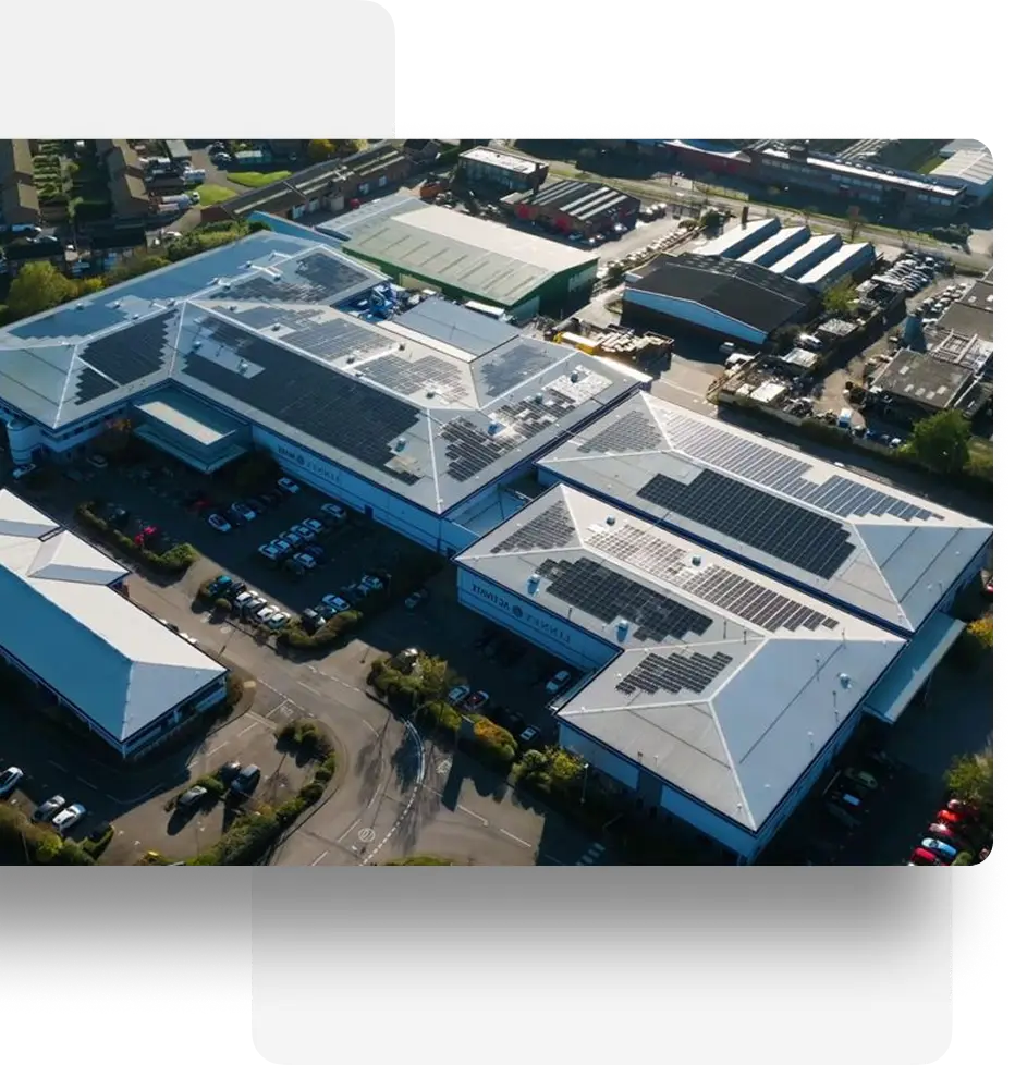 Aerial view of a commercial complex with solar panels on white rooftops, parking lots, and roads.