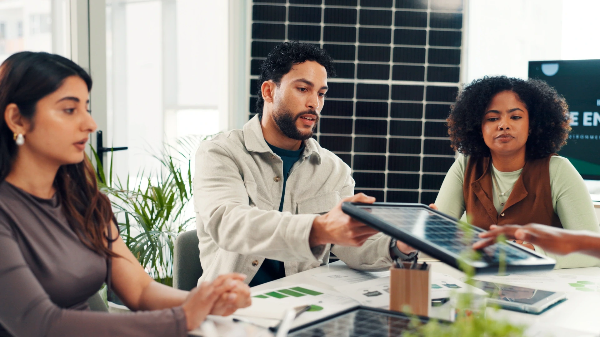 A group of professionals in a meeting reviewing a solar panel sample.