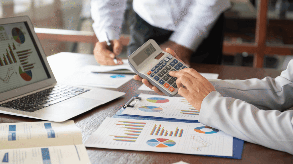 Close-up of a calculator and financial charts on a workspace table.