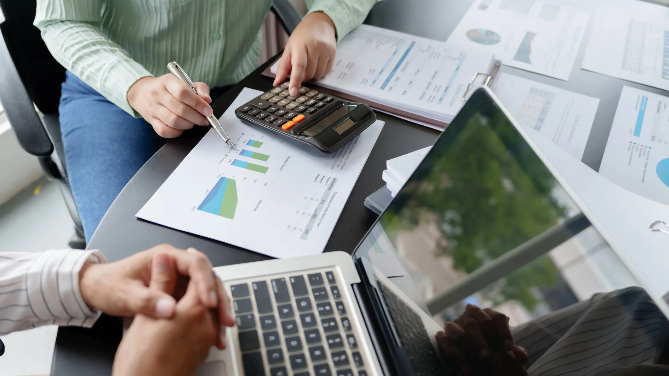 Close-up of hands working on financial charts and calculations.