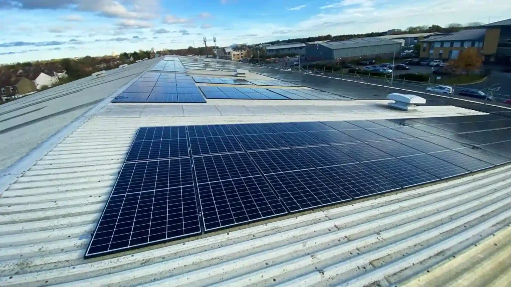 Solar panels on a large rooftop with a partly cloudy sky in the background, showcasing renewable energy usage.